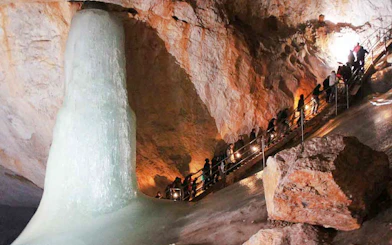 Visitors exploring Werfen Ice Caves with large ice formation, Salzburg trip.
