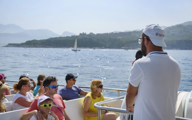 Tourists enjoying a guided boat tour along the Amalfi Coast near Sorrento.