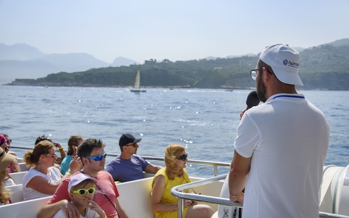 Tourists enjoying a guided boat tour along the Amalfi Coast near Sorrento.