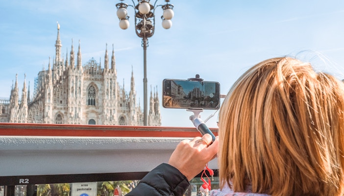 tourist taking pictures of milan duomo from the bus