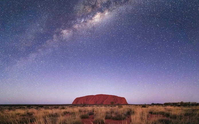 Uluru under a starry night sky, part of the 2D/1N Uluru–Kata Tjuta tour from Alice Springs.