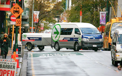 Super Shuttle van on city street for airport transfers.