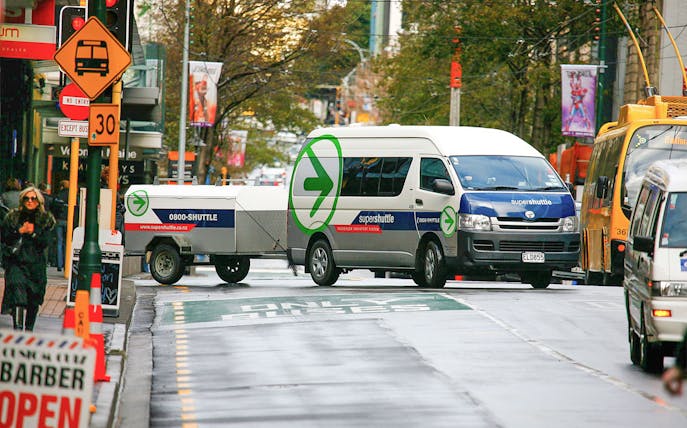 Super Shuttle van on city street for airport transfers.