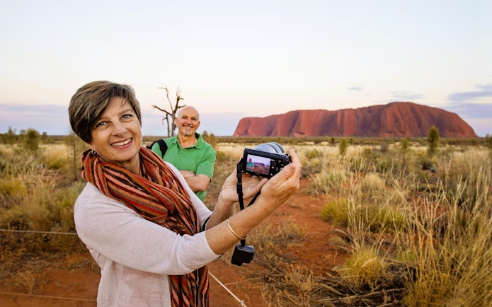Tourists taking photos at Uluru during the Outback Camping Adventure.