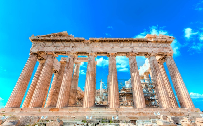 Parthenon temple with scaffolding under a clear blue sky in Athens, Greece.