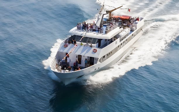 Ferry carrying passengers on Navitremiti round trip over clear blue water.