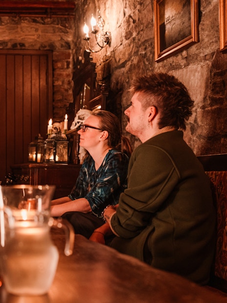 Tour guide in period costume leading an evening underground ghost tour in Edinburgh.