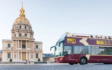 Big Bus Paris tour passing Les Invalides with tourists on board.