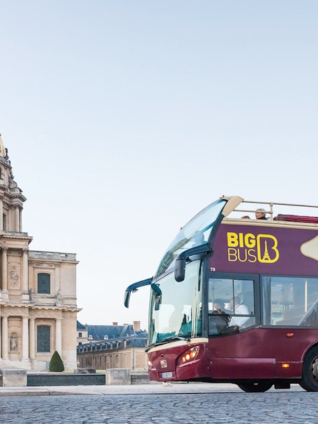 Big Bus Paris tour passing Les Invalides with tourists on board.