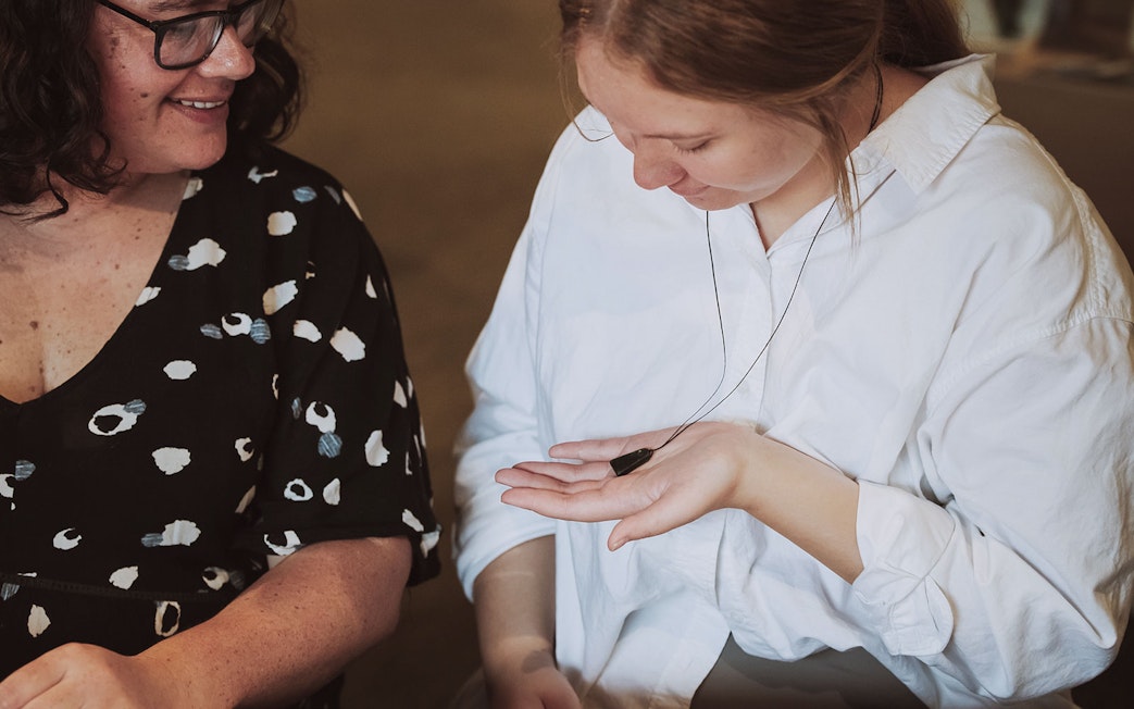 Two people examining a jade pendant during the Mountain Jade Highlights Tour.