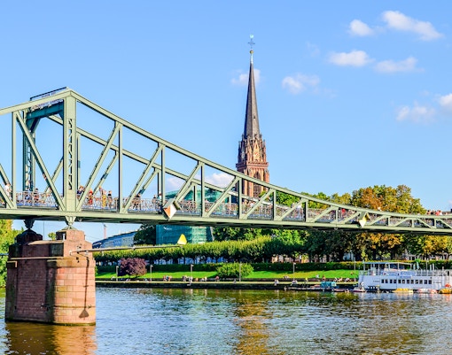 Iron Footbridge over river with spire in background, Frankfurt, Germany.
