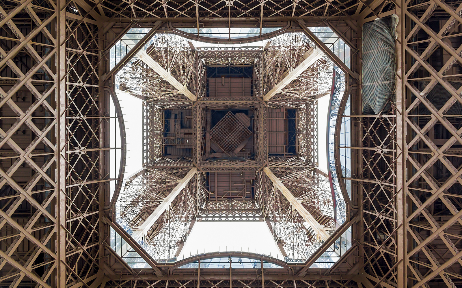View from beneath the Eiffel Tower's intricate iron structure during guided elevator tour.