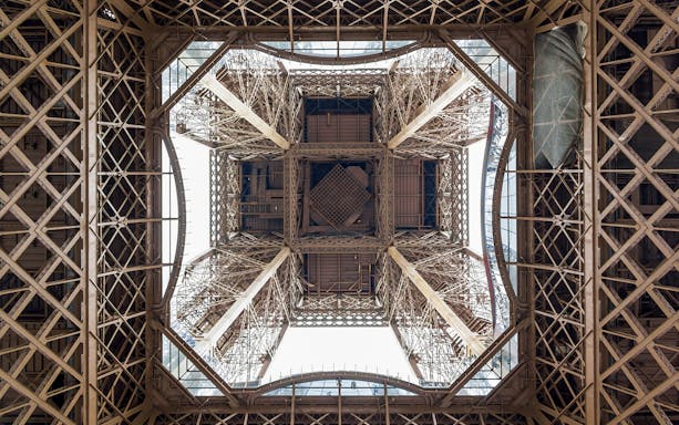 View from beneath the Eiffel Tower's intricate iron structure during guided elevator tour.