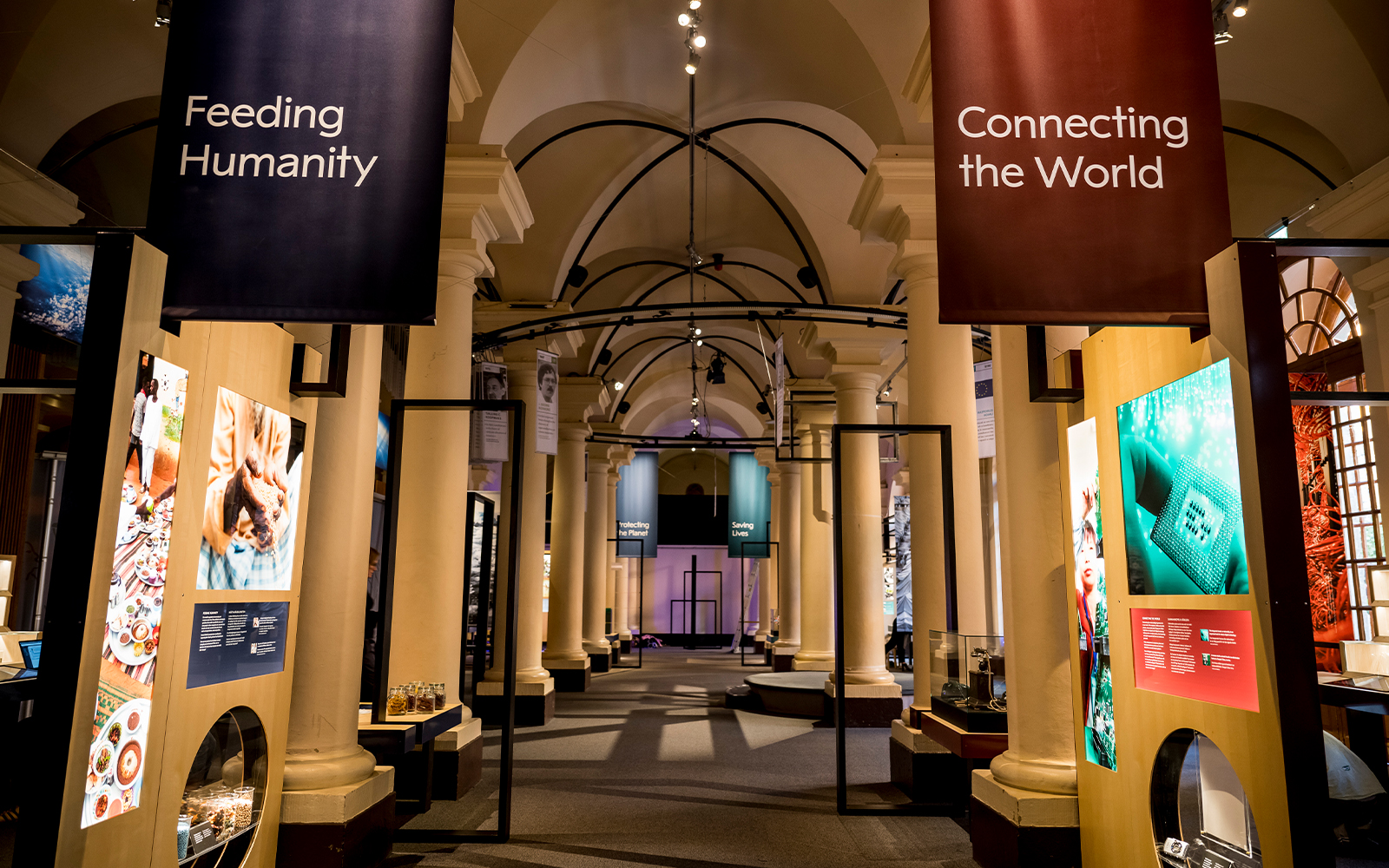 Stockholm museum exhibit with banners "Feeding Humanity" and "Connecting the World" in a columned hall.