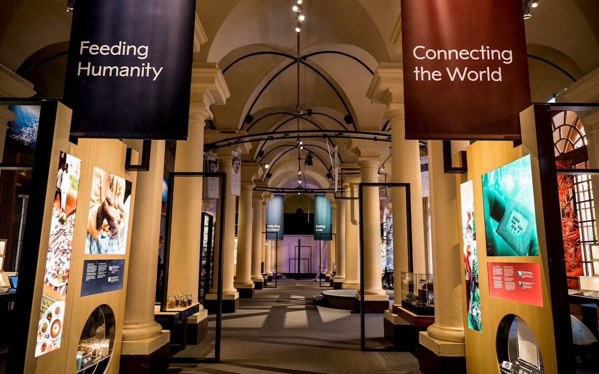 Stockholm museum exhibit with banners "Feeding Humanity" and "Connecting the World" in a columned hall.