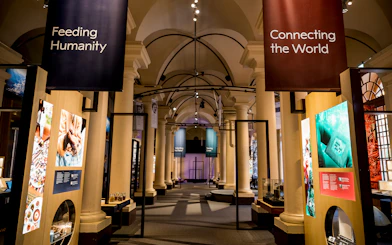 Stockholm museum exhibit with banners "Feeding Humanity" and "Connecting the World" in a columned hall.