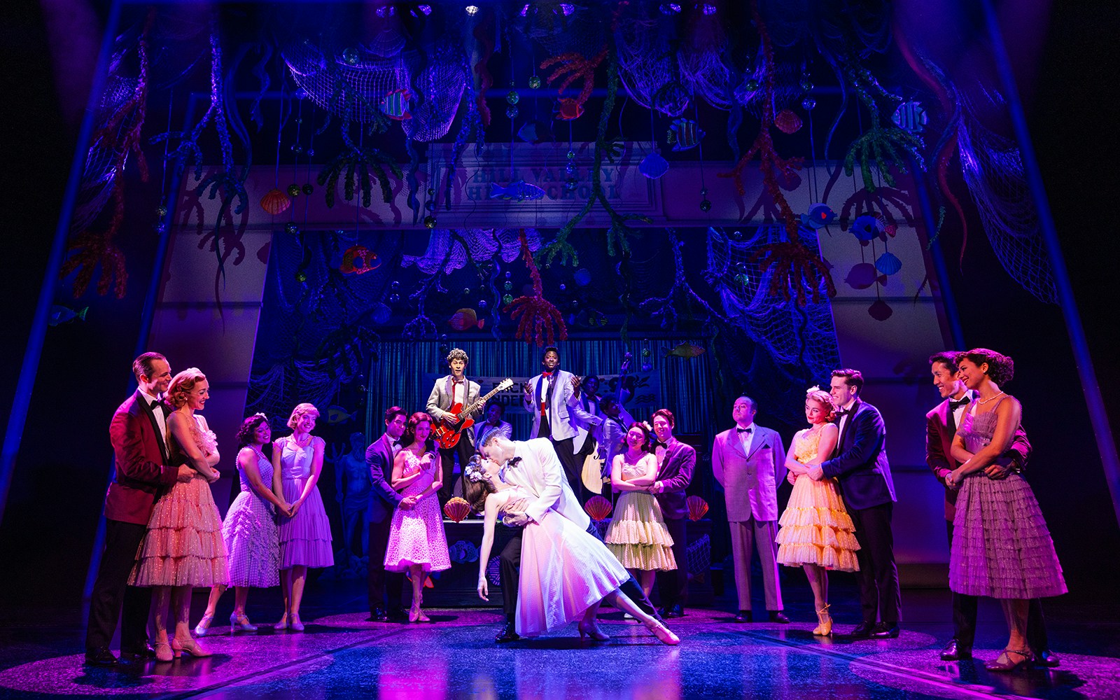 Cast performing a dance scene in "Back to the Future the Musical" with vibrant stage decor.