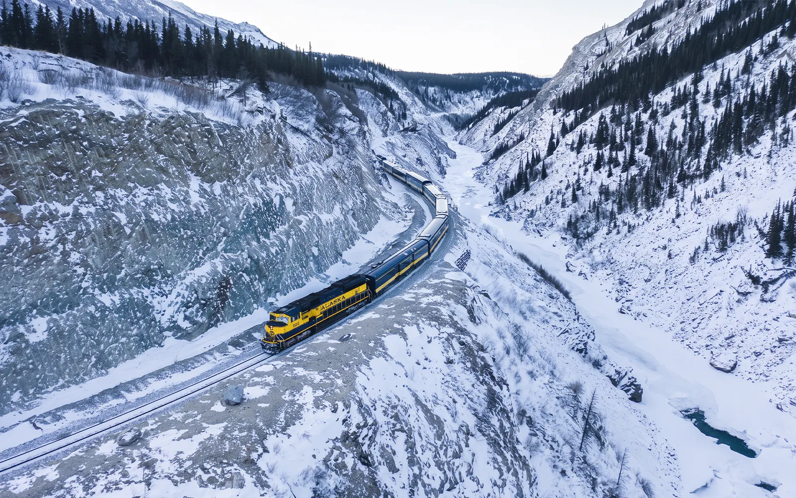 Aurora Winter Train traveling through snowy Alaskan mountains on the Alaska Railroad.