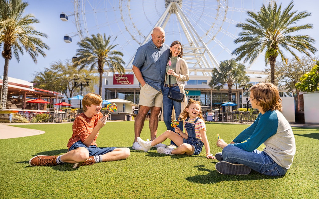 Family enjoying time at ICON Park, Orlando with the Ferris wheel in the background.