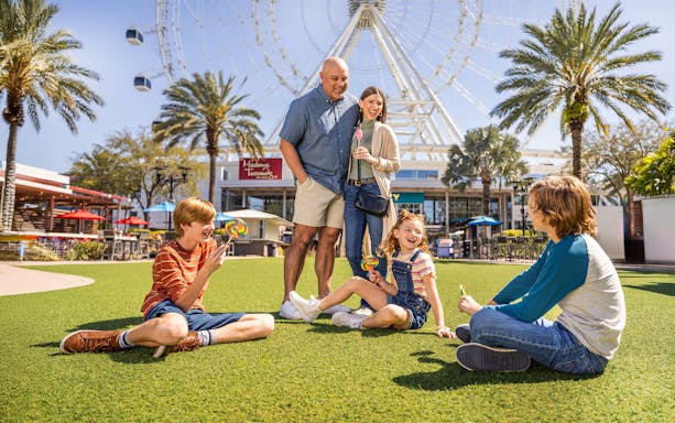 Family enjoying time at ICON Park, Orlando with the Ferris wheel in the background.