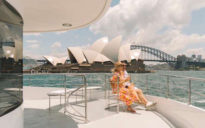 Couple enjoying Sydney Harbour dinner cruise with Opera House and Harbour Bridge views.