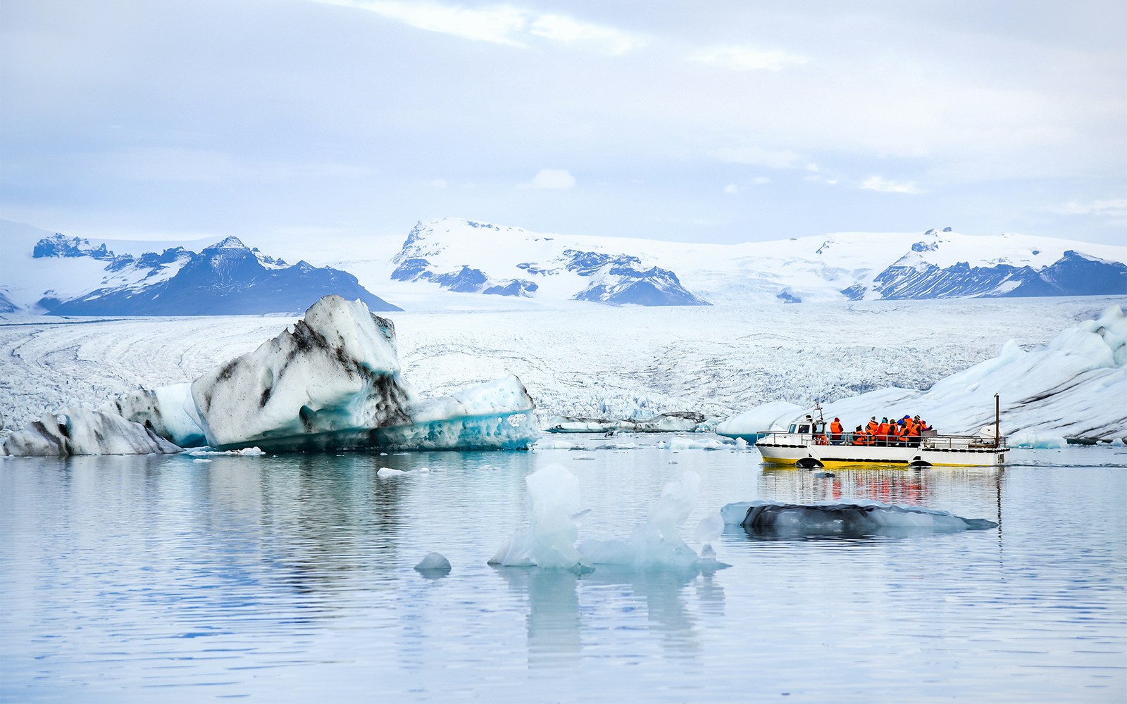 Tourists on a boat tour in Jokulsarlon glacial lagoon with icebergs, Iceland.