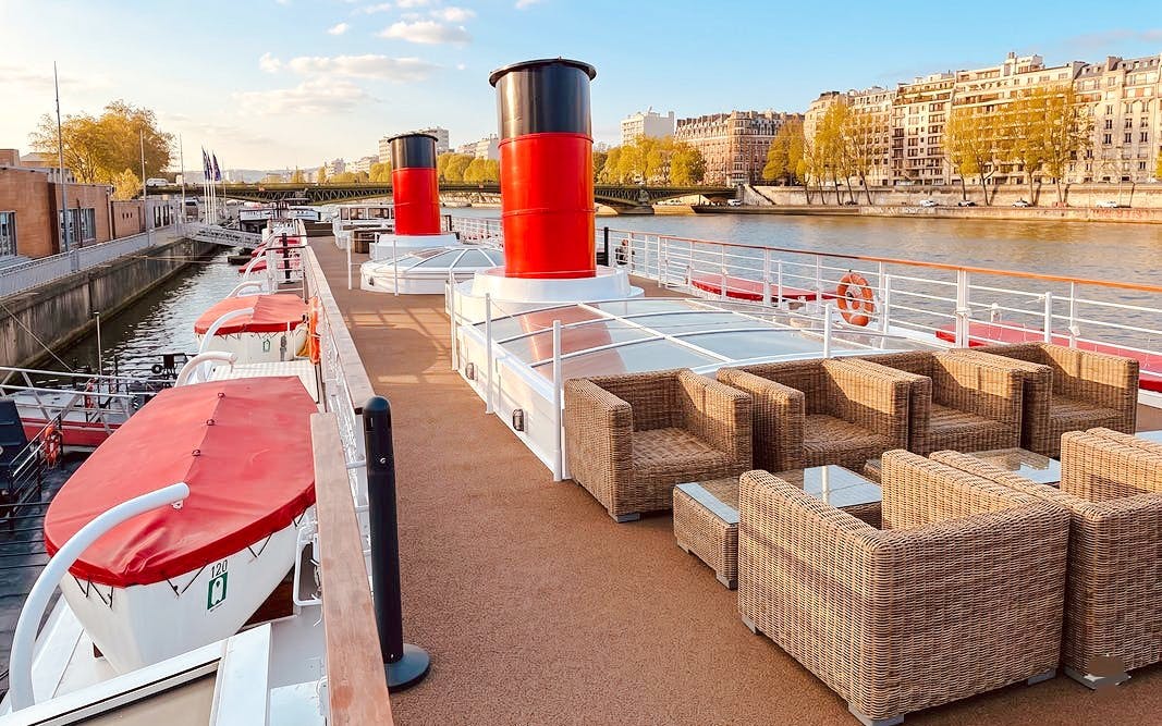 Deck of a Seine River cruise ship with seating, Paris Bastille Day Dinner Cruise.