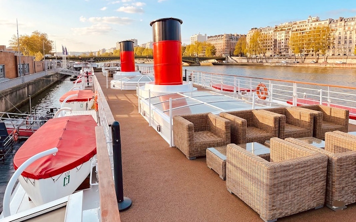 Deck of a Seine River cruise ship with seating, Paris Bastille Day Dinner Cruise.