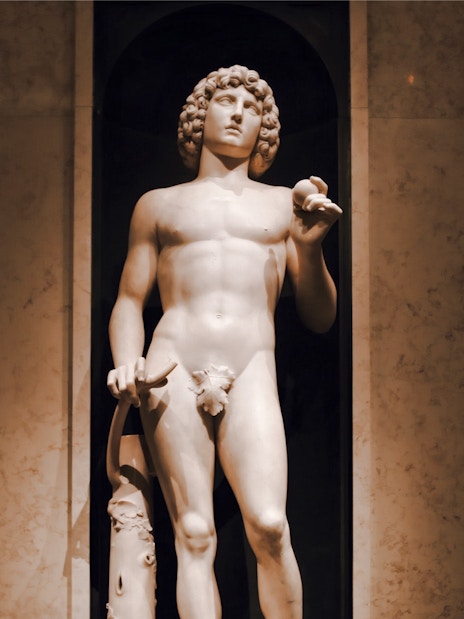 Marble sculpture of Adam by Tullio Lombardo, holding an apple and broken tree branch.