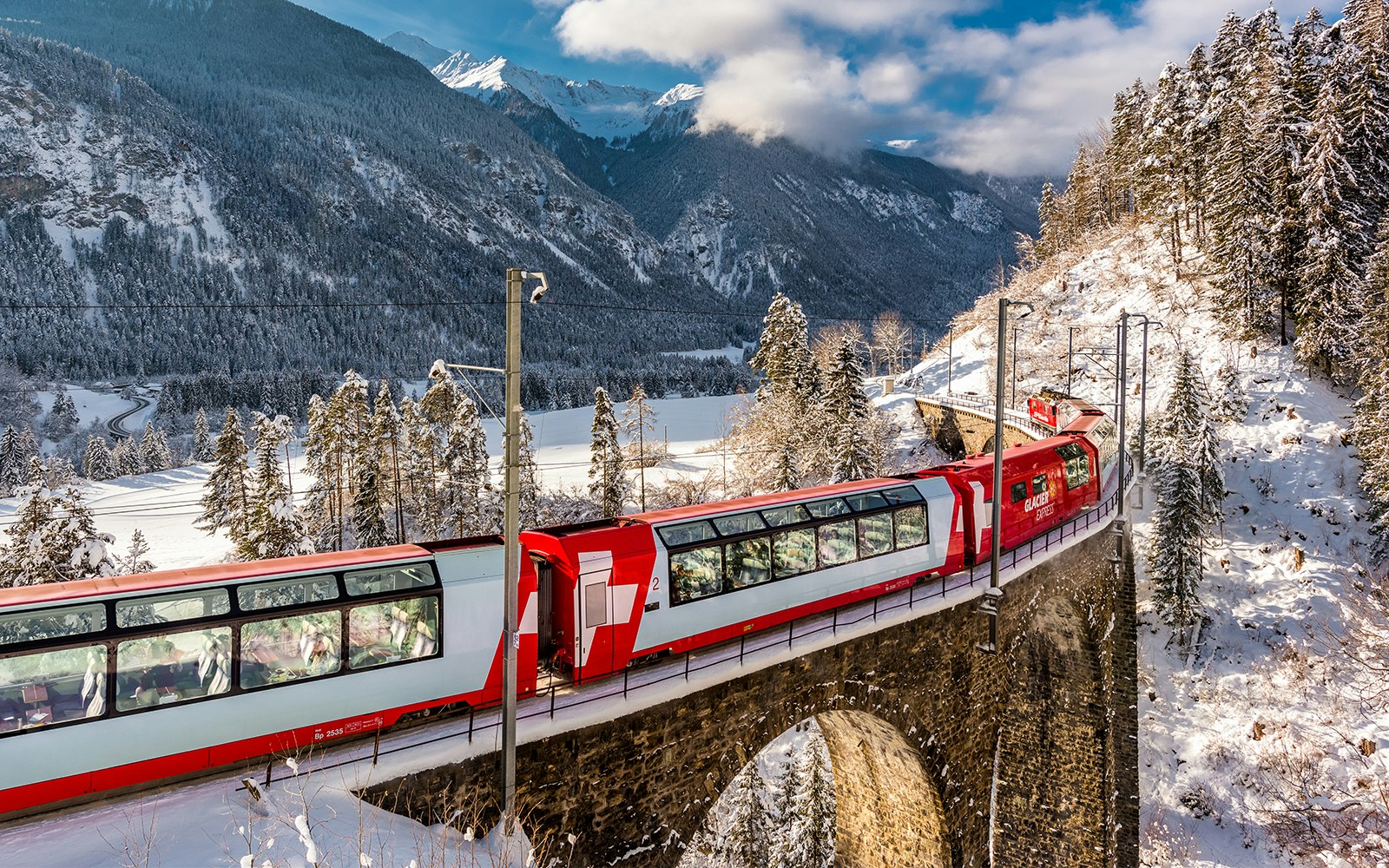 Glacier Express train crossing a scenic bridge in the Swiss Alps.