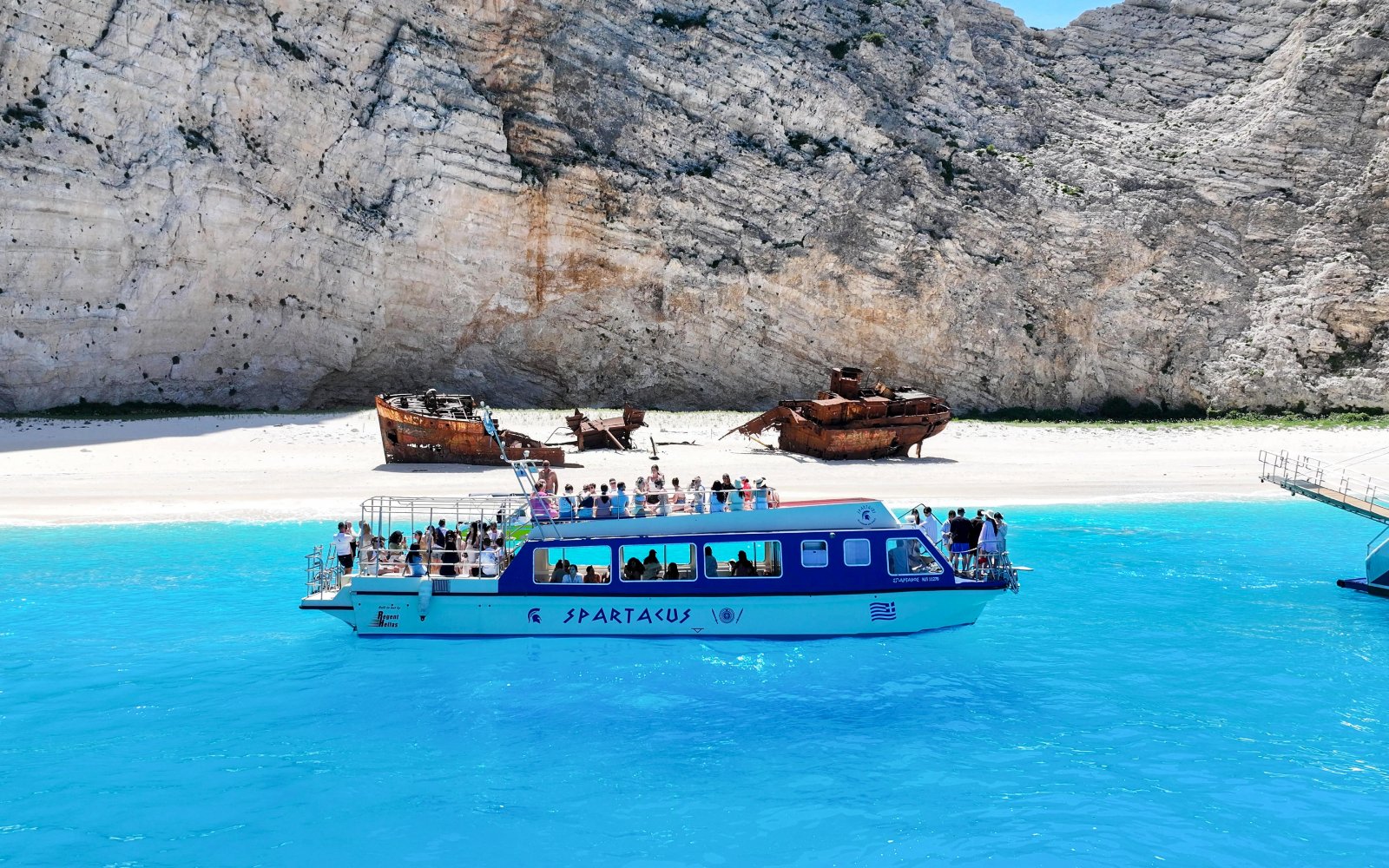 Glass bottom boat near Navagio Beach with shipwreck in background, Zakynthos, Greece.