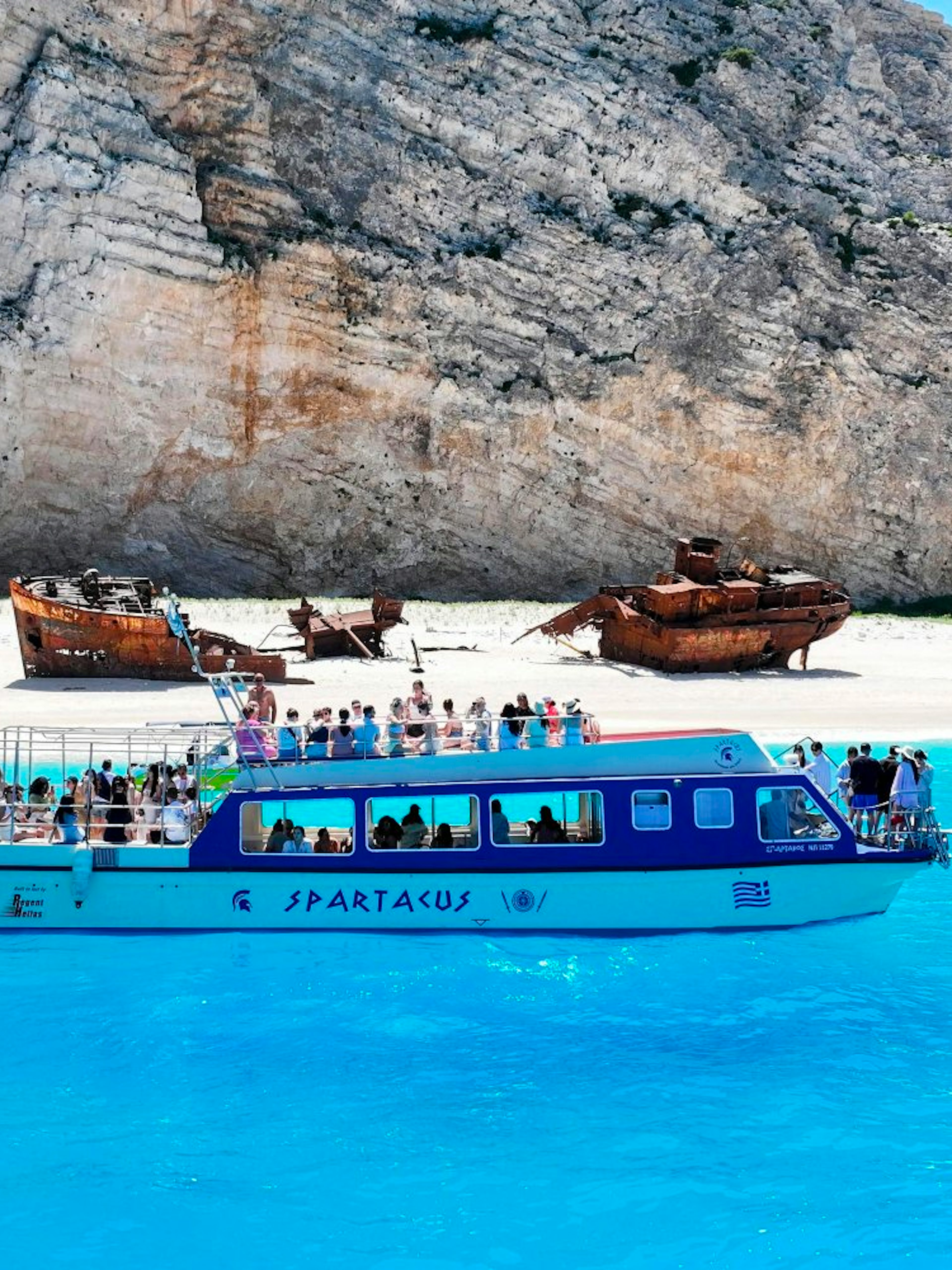 Glass bottom boat near Navagio Beach with shipwreck in background, Zakynthos, Greece.