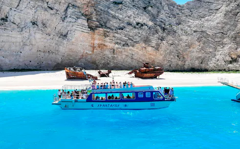 Glass bottom boat near Navagio Beach with shipwreck in background, Zakynthos, Greece.