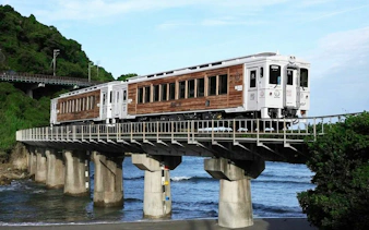 Train crossing a coastal bridge in Kyushu, Japan, part of the JR PASS rail tour.