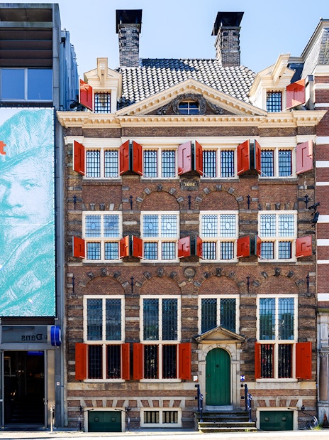 Exteriors of the Rembrandt House Museum in Amsterdam with red shutters and historic architecture.