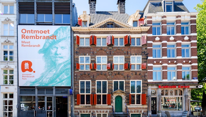 Exteriors of the Rembrandt House Museum in Amsterdam with red shutters and historic architecture.