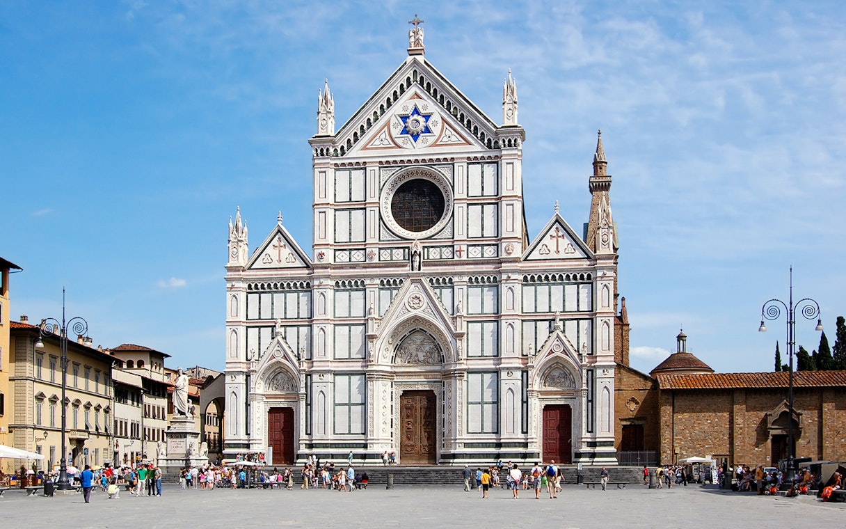 Santa Croce Basilica facade in Florence, Italy, with tourists in the foreground.