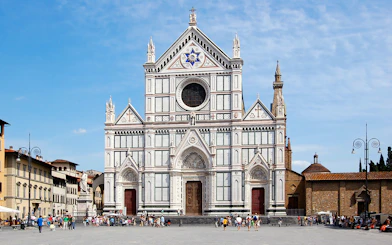 Santa Croce Basilica facade in Florence, Italy, with tourists in the foreground.