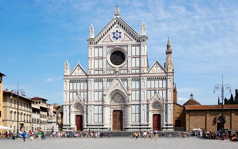 Santa Croce Basilica facade in Florence, Italy, with tourists in the foreground.