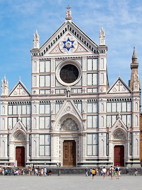 Santa Croce Basilica facade in Florence, Italy, with tourists in the foreground.