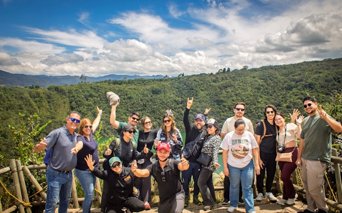 Tourists posing in front of Guatavita Lake, Colombia, with lush greenery in the background.
