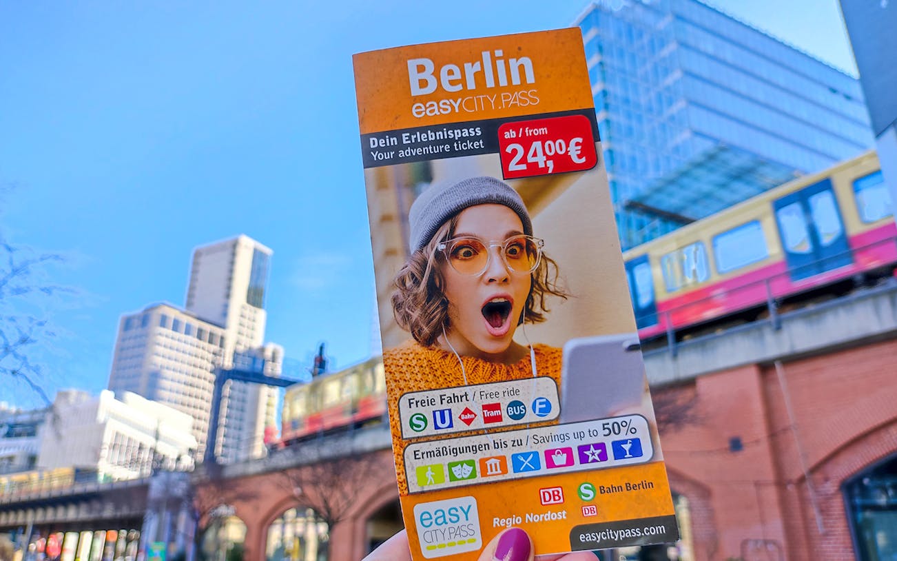 Berlin EasyCityPass brochure with public transport and discount details, cityscape in background.