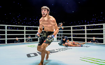 Muay Thai fighter celebrating victory at One Lumpinee Boxing Stadium.