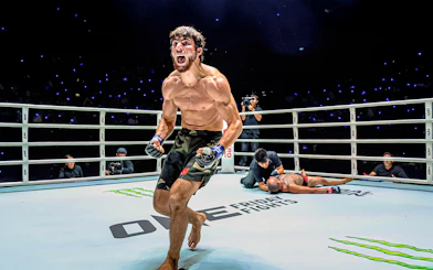 Muay Thai fighter celebrating victory at One Lumpinee Boxing Stadium.
