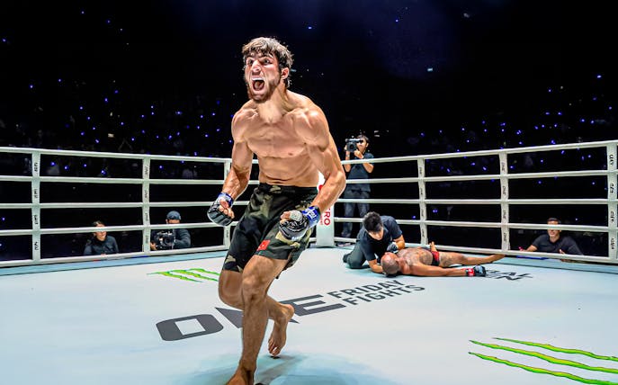 Muay Thai fighter celebrating victory at One Lumpinee Boxing Stadium.