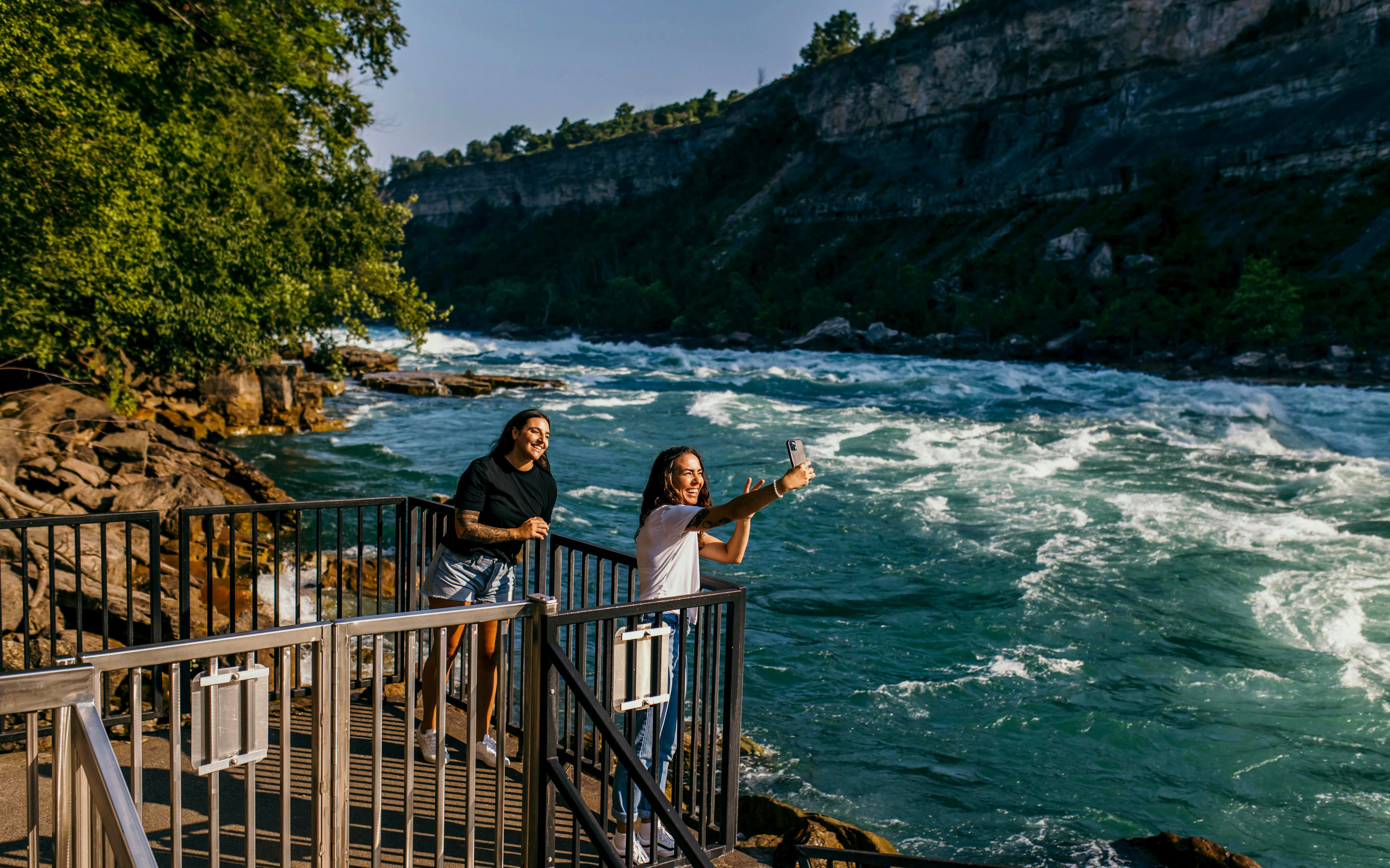Visitors taking photos at White Water Walk, Niagara River rapids in the background.