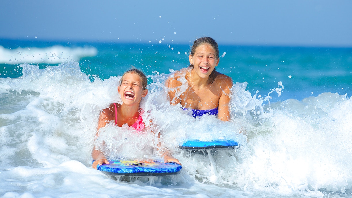 Kids enjoying bodyboarding in ocean waves.