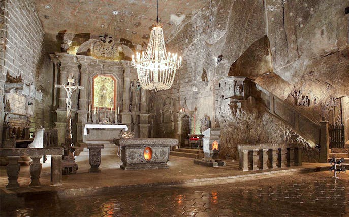 Wieliczka Salt Mine chapel interior with altar, chandelier, and carved salt walls.