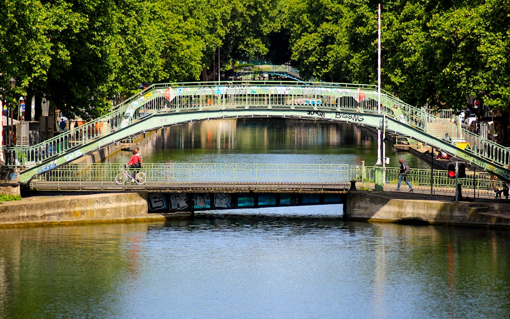 Canal Saint-Martin bridge in Paris with cyclist and pedestrian crossing.