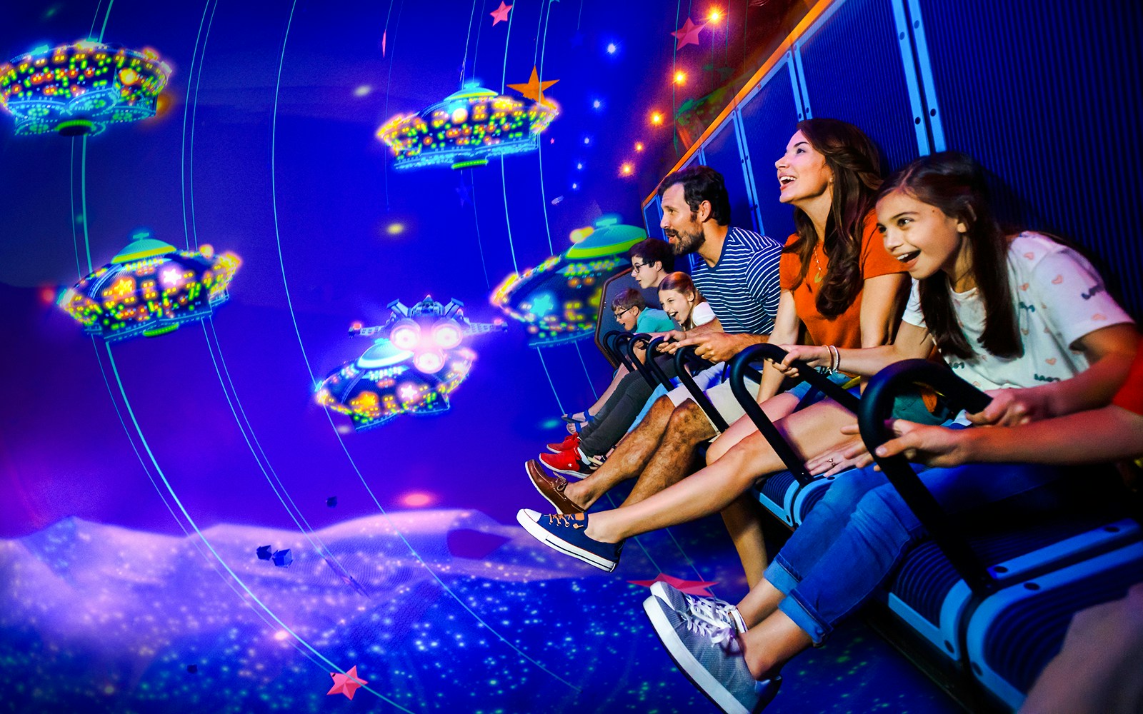 Family enjoying a 3D ride at LEGOLAND® California with colorful UFOs in the background.